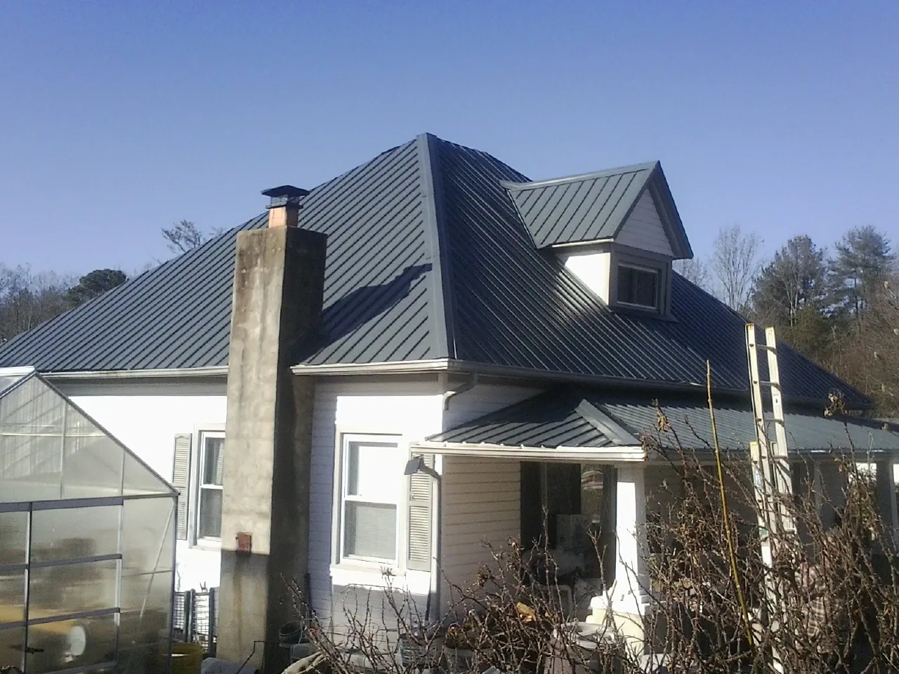 Dark blue standing seam metal roof on a white farmhouse with dormer — Slate & Tile Roof Repair by Roofing Brothers in Kevil