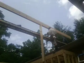 Carpenter setting a ridge beam over a new addition frame — Ice Dam Removal by Roofing Brothers in Kevil