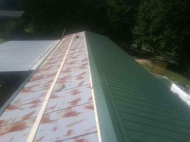 Old rusted panels beside newly installed green metal roofing — Wind Damage Roof Repair by Roofing Brothers in Kevil