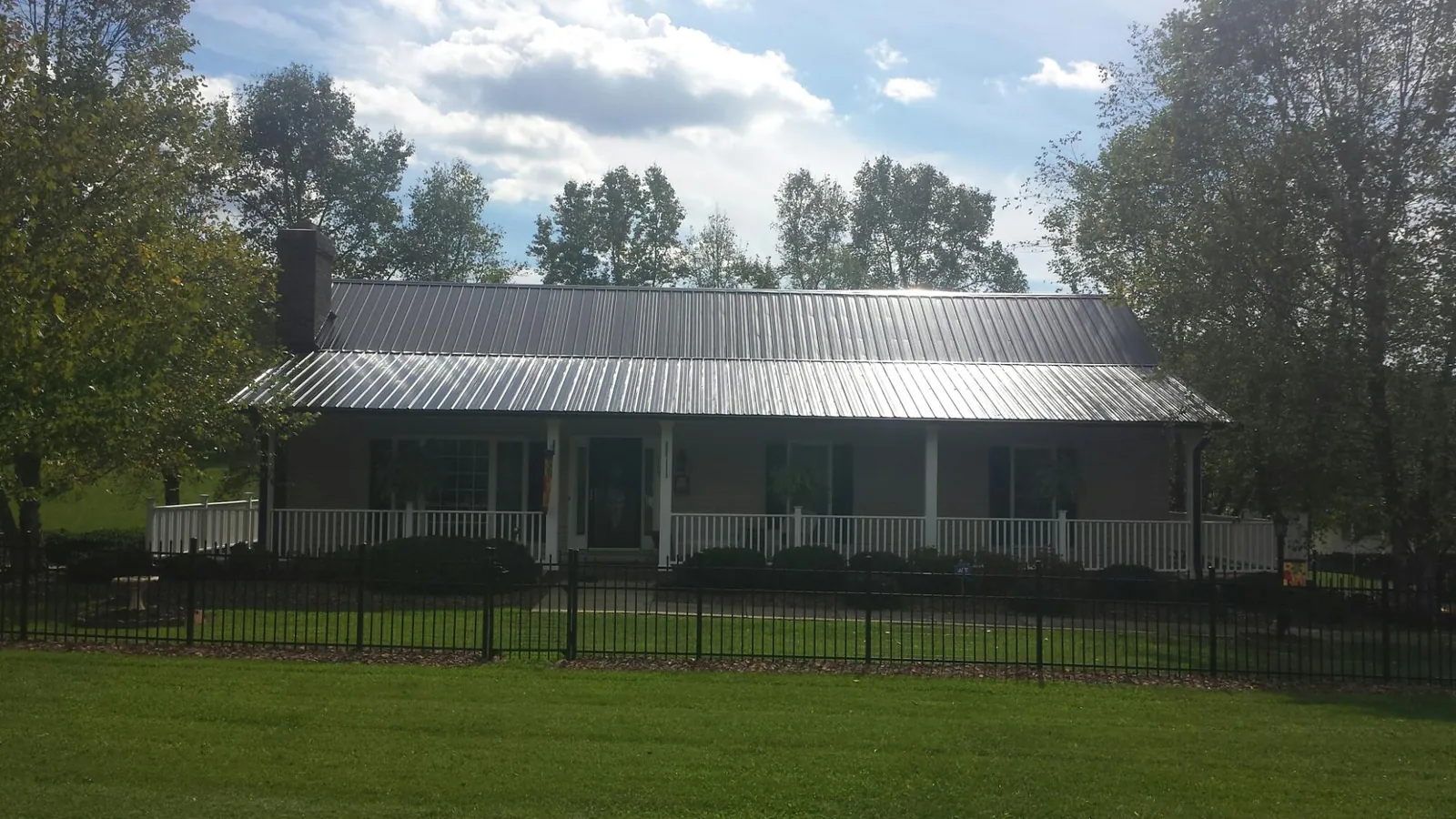 Gray metal roof on a brick ranch with a full width front porch — Gutter Guard Installation work by our crew in Kevil
